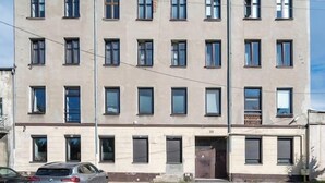 A multi-story building with a flat facade, several windows, and a car parked in front. - Łódź Płocka Apt – Parks & Public Transport nearby (Łódź)
