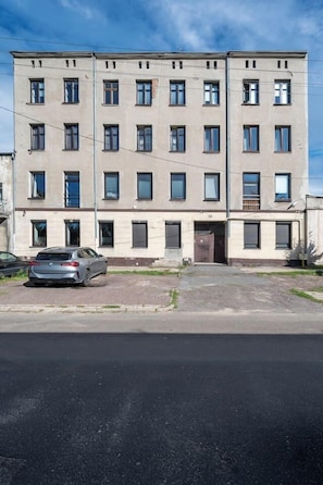 En byggnad med flera våningar och en slät fasad, med flera fönster och en bil parkerad framför.