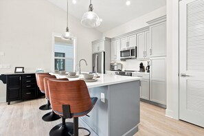 A modern kitchen with white cabinets, stainless steel appliances, and a central island with seating. - Island Hop - Steps From Fort Myers Beach (Fort Myers Beach)