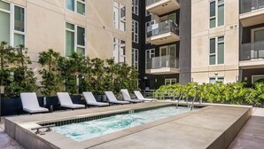 Área de piscina no terraço, com espreguiçadeiras e banheira de hidromassagem.