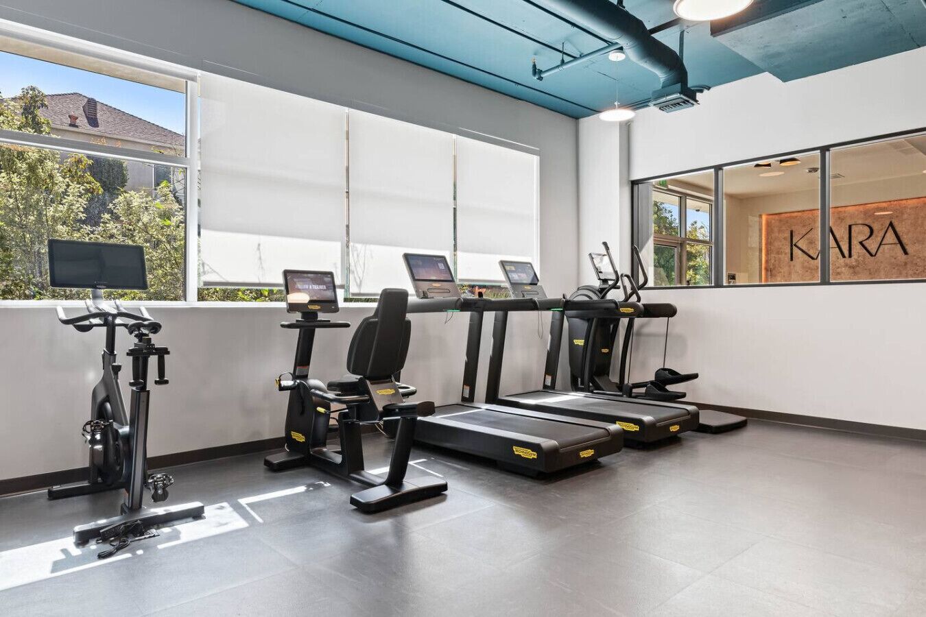 Ein Fitnessstudio mit Laufbändern, einem Ergometer und einem Rudergerät.