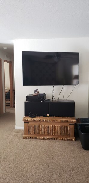 Ein Flachbildfernseher an der Wand, darunter ein Unterhaltungsschrank aus Holz.