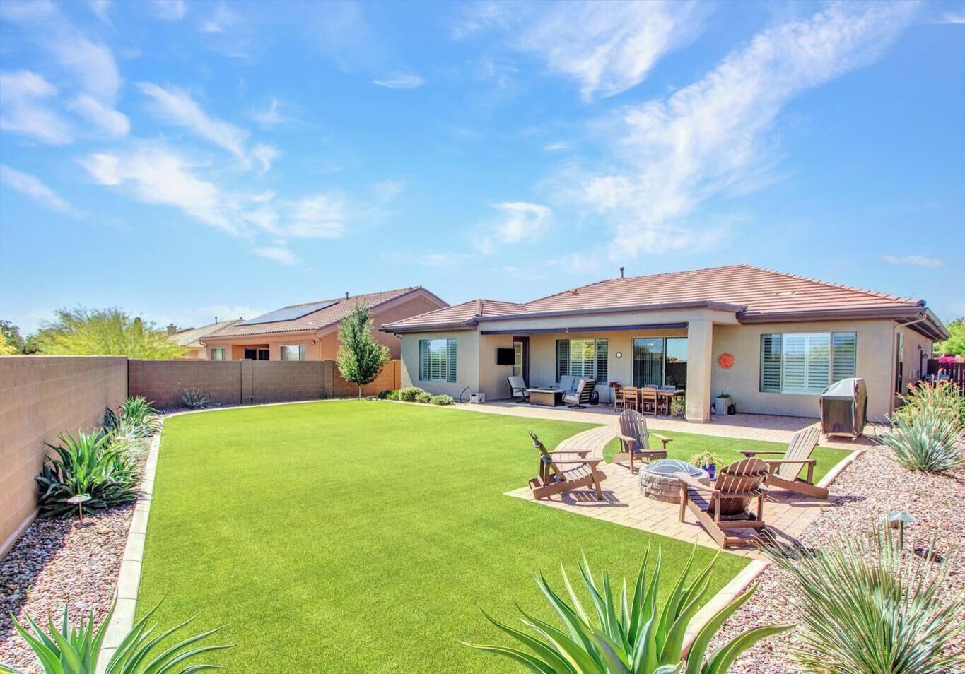 A residential property with a covered patio, outdoor seating, and a well-maintained lawn.