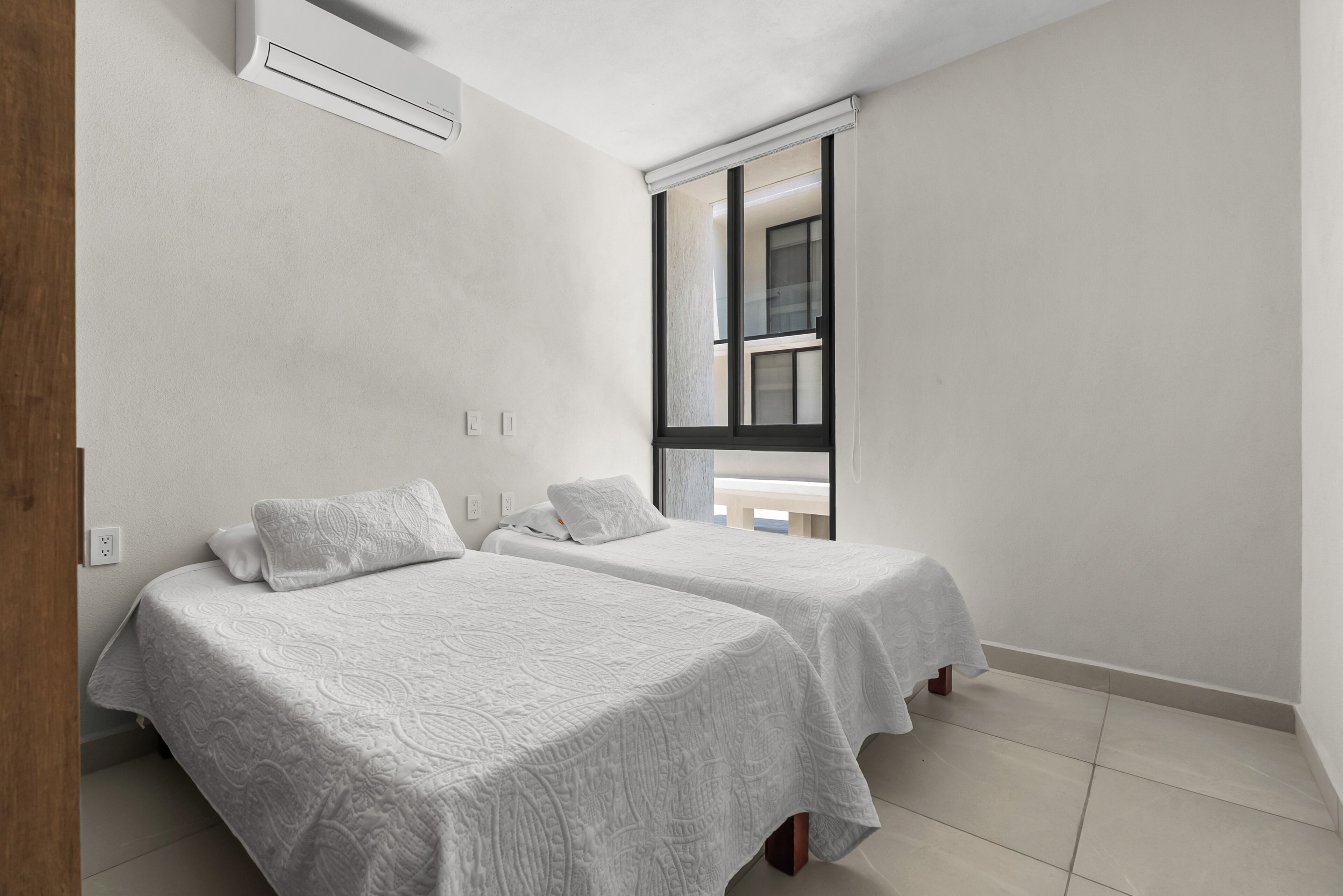 Una camera da letto con due letti, una finestra e un condizionatore d'aria.