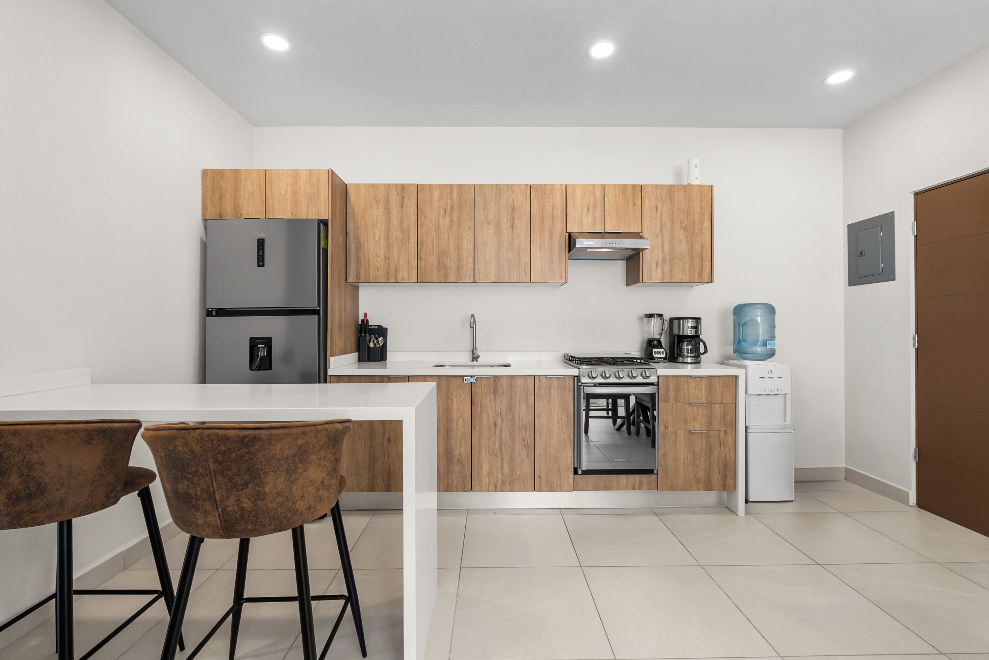Una cocina moderna con armarios de madera, electrodomésticos de acero inoxidable y encimera blanca.