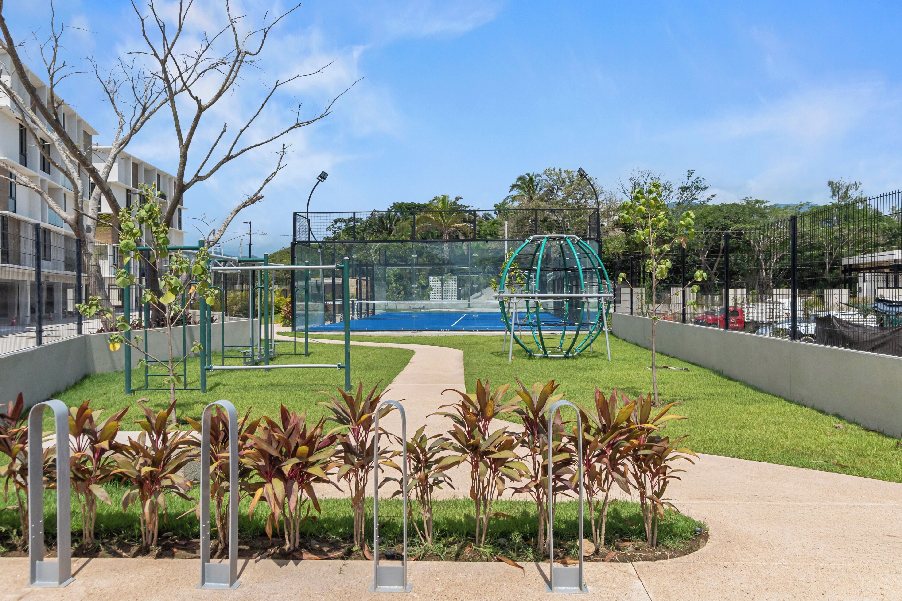 Un parque infantil con suelo azul, rodeado por una valla y varios equipos de ejercicio.