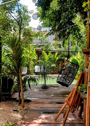 Una terraza de madera con una silla colgante y plantas en macetas.