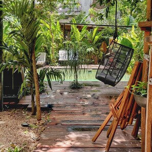 Una terraza de madera con una silla colgante y plantas en macetas.