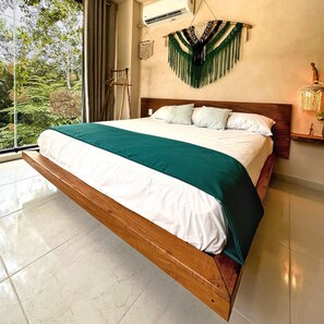 Un dormitorio moderno con una cama grande, cabecera de madera y vista a zonas verdes.