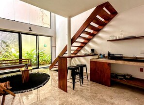 Una cocina moderna con una escalera de madera, una zona de comedor con banco y vistas al exterior.