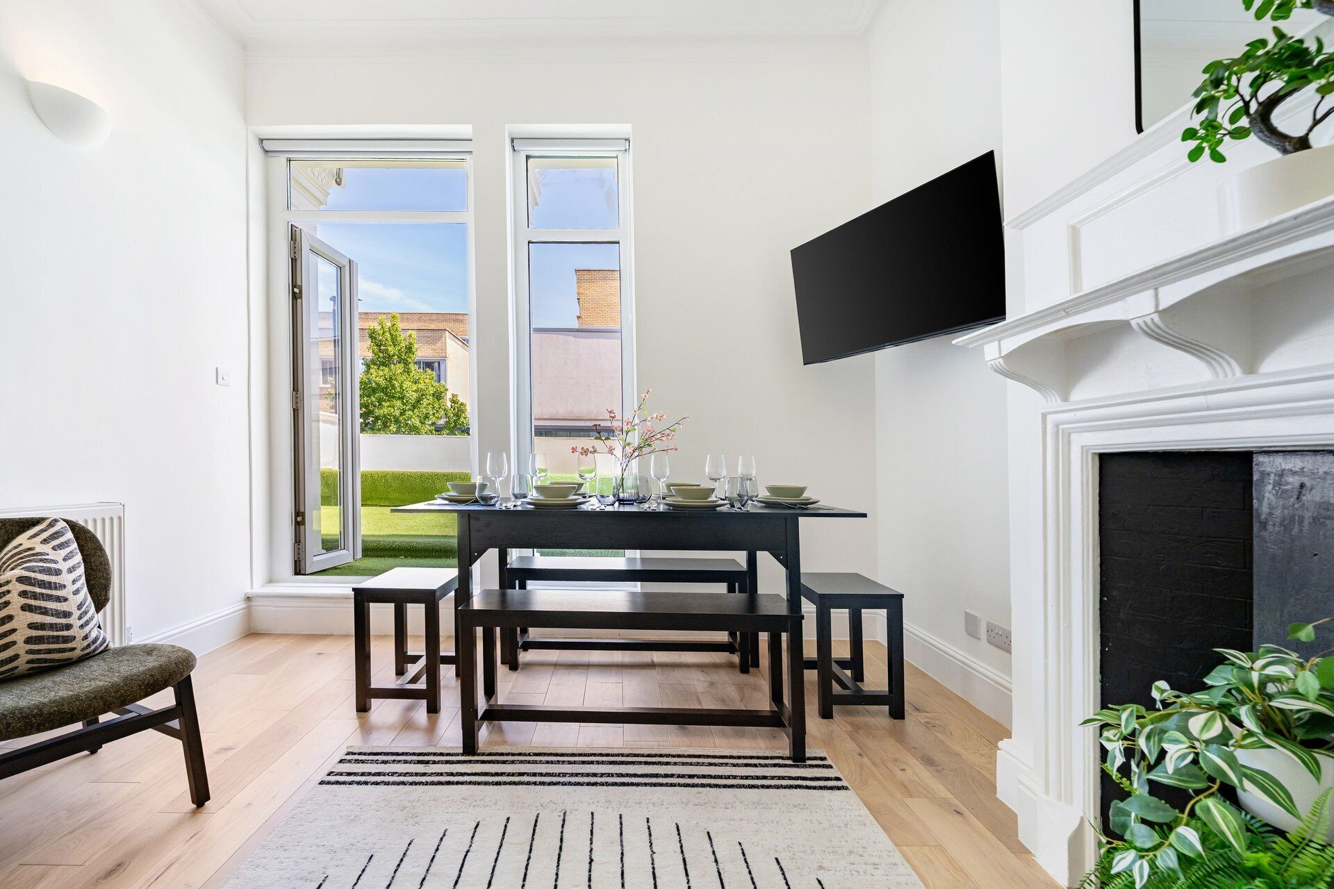 A dining area with a table set for four, a fireplace, and a television mounted above it.
