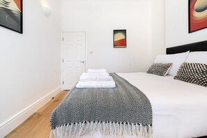 Ett hotellrum med en säng, en dörr och en vägg med konstverk.