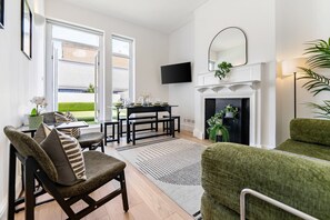Una sala moderna con chimenea, un comedor y un área de estar con un sofá verde y una silla.