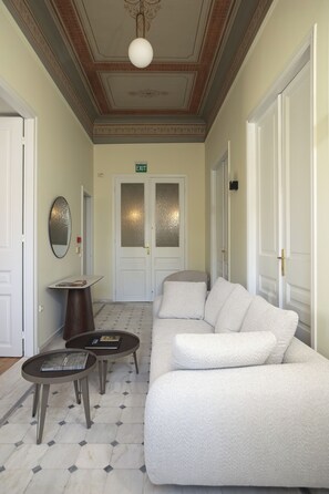 A hallway with a white sofa, two small tables, and a mirror on the wall. - A neoclassical monument with Acropolis view in the Historic Center of Athens (Athina)