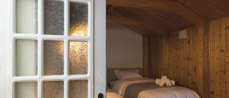 A room with a bed, wooden walls, and a door with frosted glass panels.