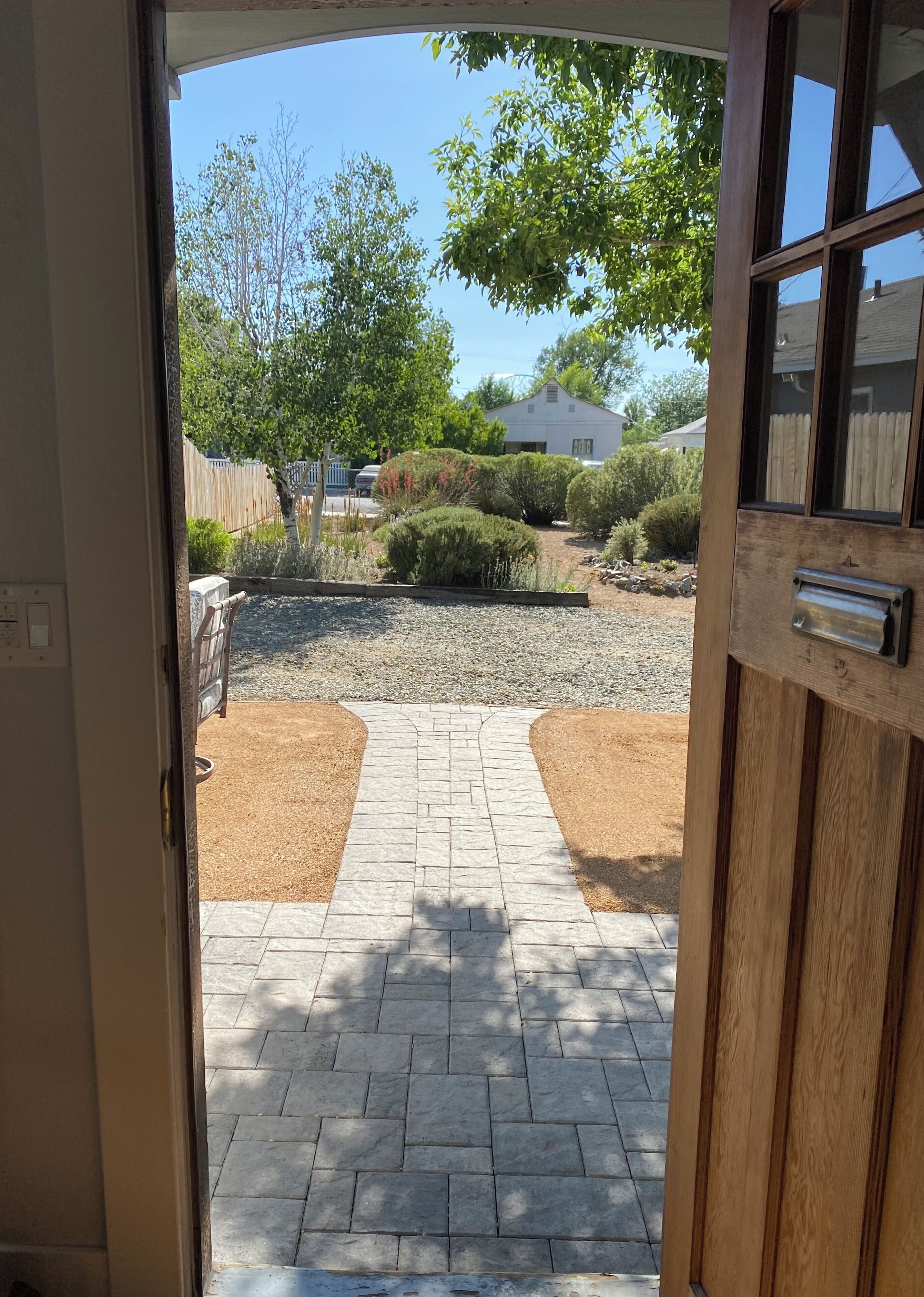 A paved pathway leading to a landscaped area with shrubs and a gravel section.