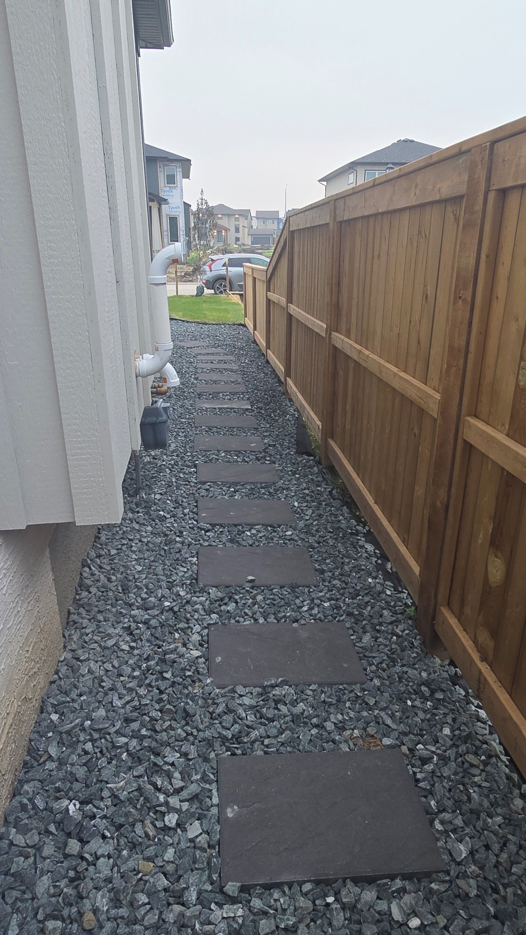 Un sentier bordé de pierres plates qui mène à une clôture en bois.