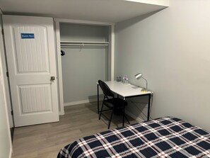A room with a bed, a desk with a chair, a desk lamp, and a water bottle. There is a door with a sign indicating 'Room No.2'. - Clean, bright, modern room with a cozy queen bed, perfect for two adults. (Spruce Grove)