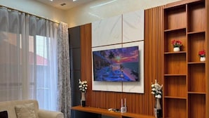 Ett modernt vardagsrum med en soffa, ett soffbord och en tv som är monterad på en väggpanel av trä.