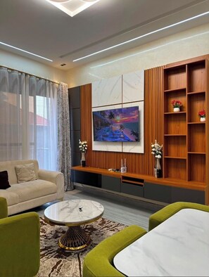 A modern living room with a sofa, a coffee table, and a TV mounted on a wooden wall. - Cassie Homes (Kampala)