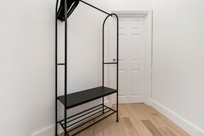 Ein Metallregal mit einer einzelnen Ablage vor einer weißen Wand, neben einer weißen Tür.