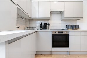 Eine moderne Küche mit weißen Schränken, einem eingebauten Backofen und einer Edelstahl-Dunstabzugshaube.