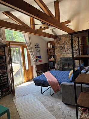 Ein Schlafzimmer mit Bett, Steinwand, Kamin, Bücherregal und einem Fenster mit Vorhängen.