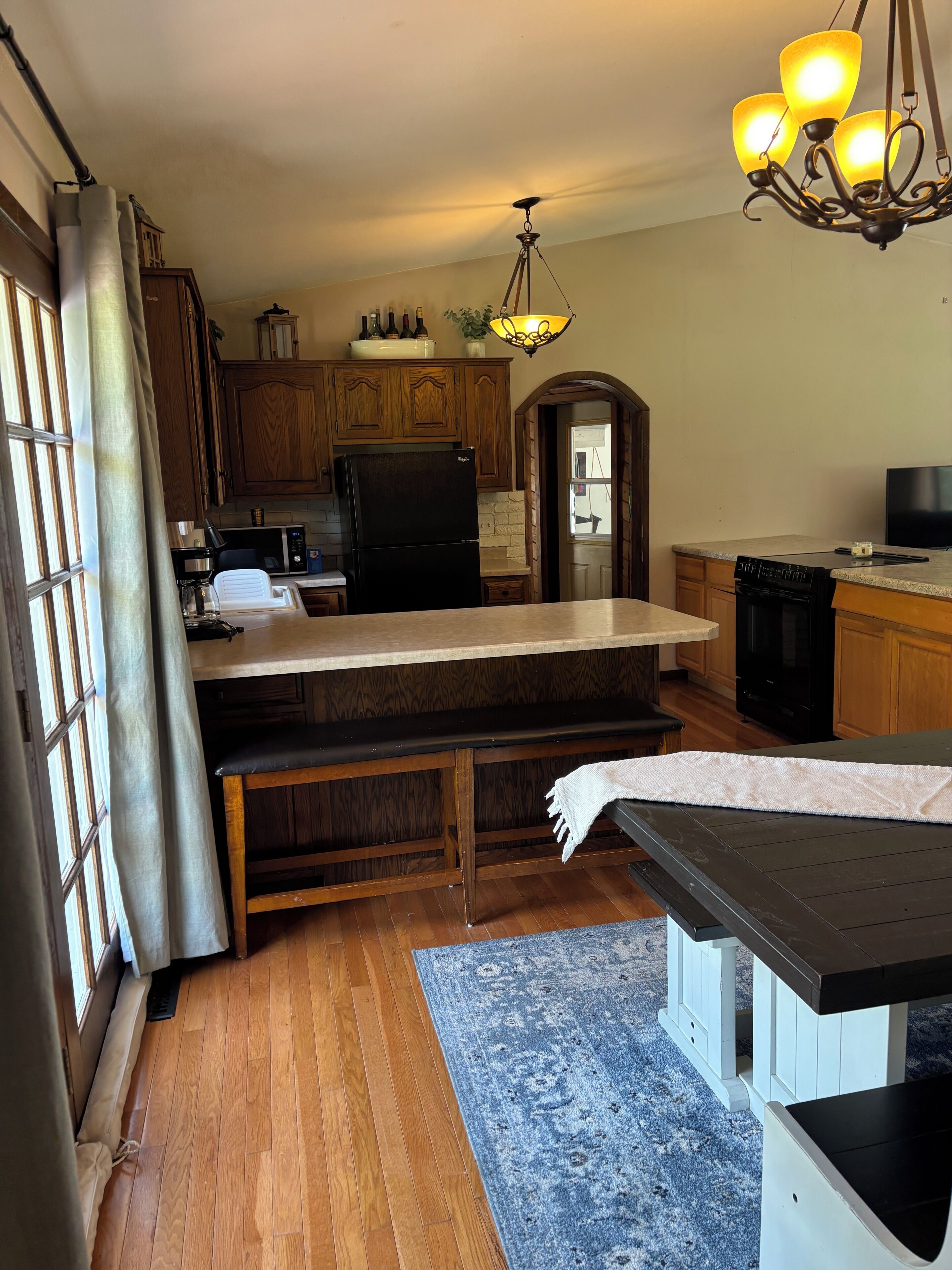 A kitchen with wooden cabinets, a black refrigerator, a microwave, and a stove.