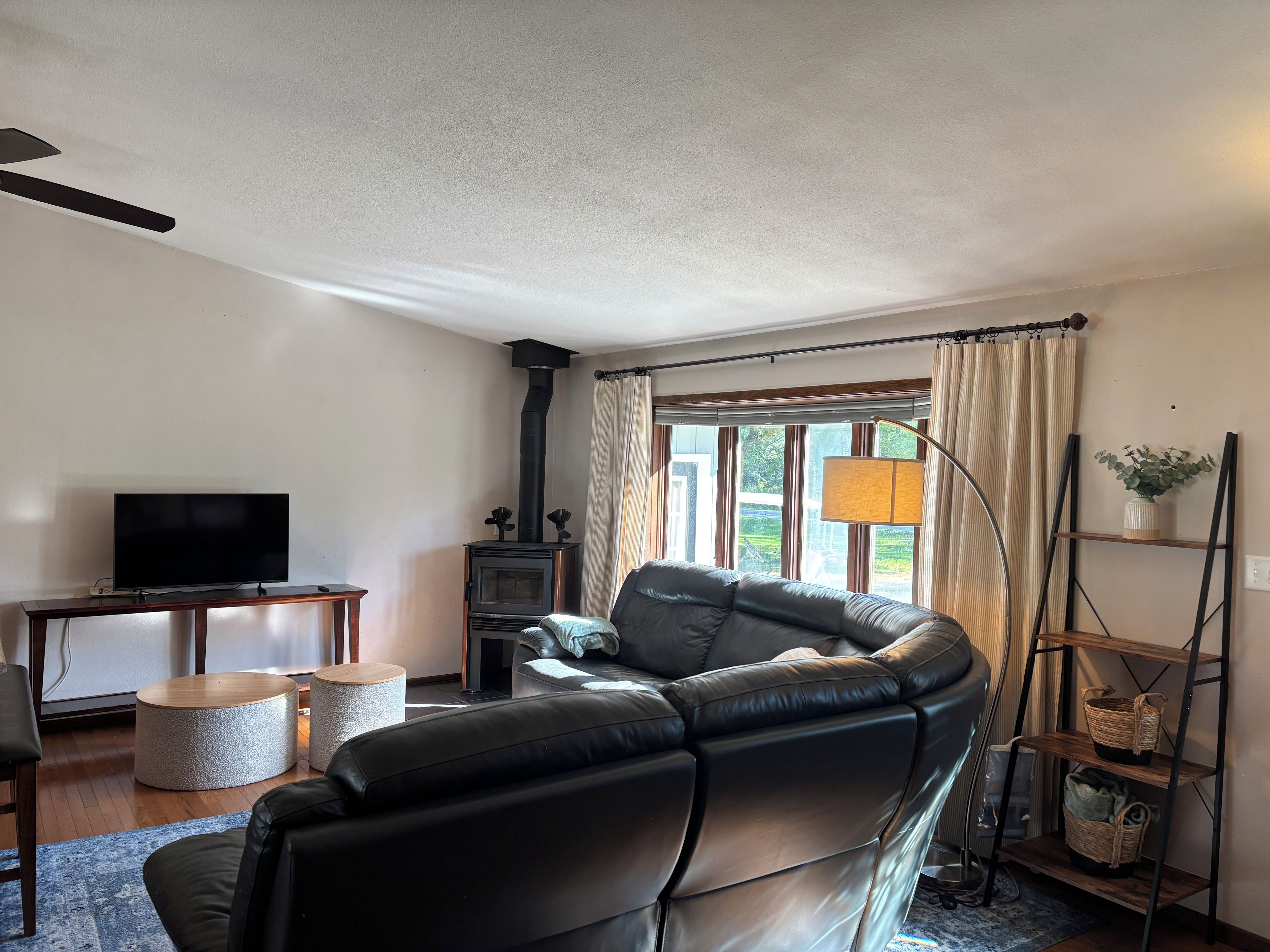 Una sala de estar con un sofá de cuero, televisor, chimenea y una ventana con cortinas.