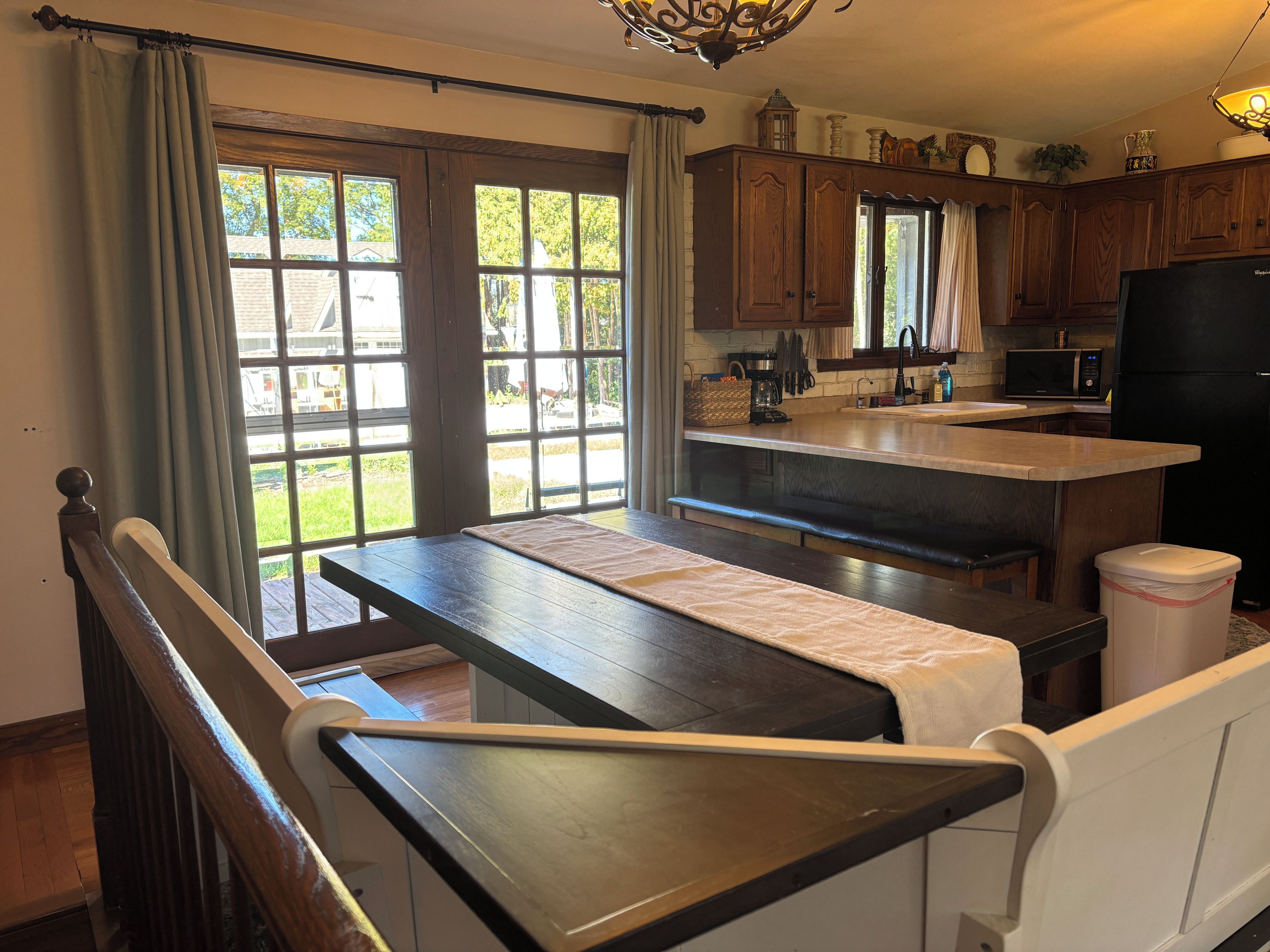 A kitchen with a wooden bench, a dining table, and a refrigerator.