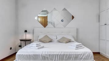 Una camera da letto con un letto, due cuscini, un comodino con una lampada e uno specchio a parete.