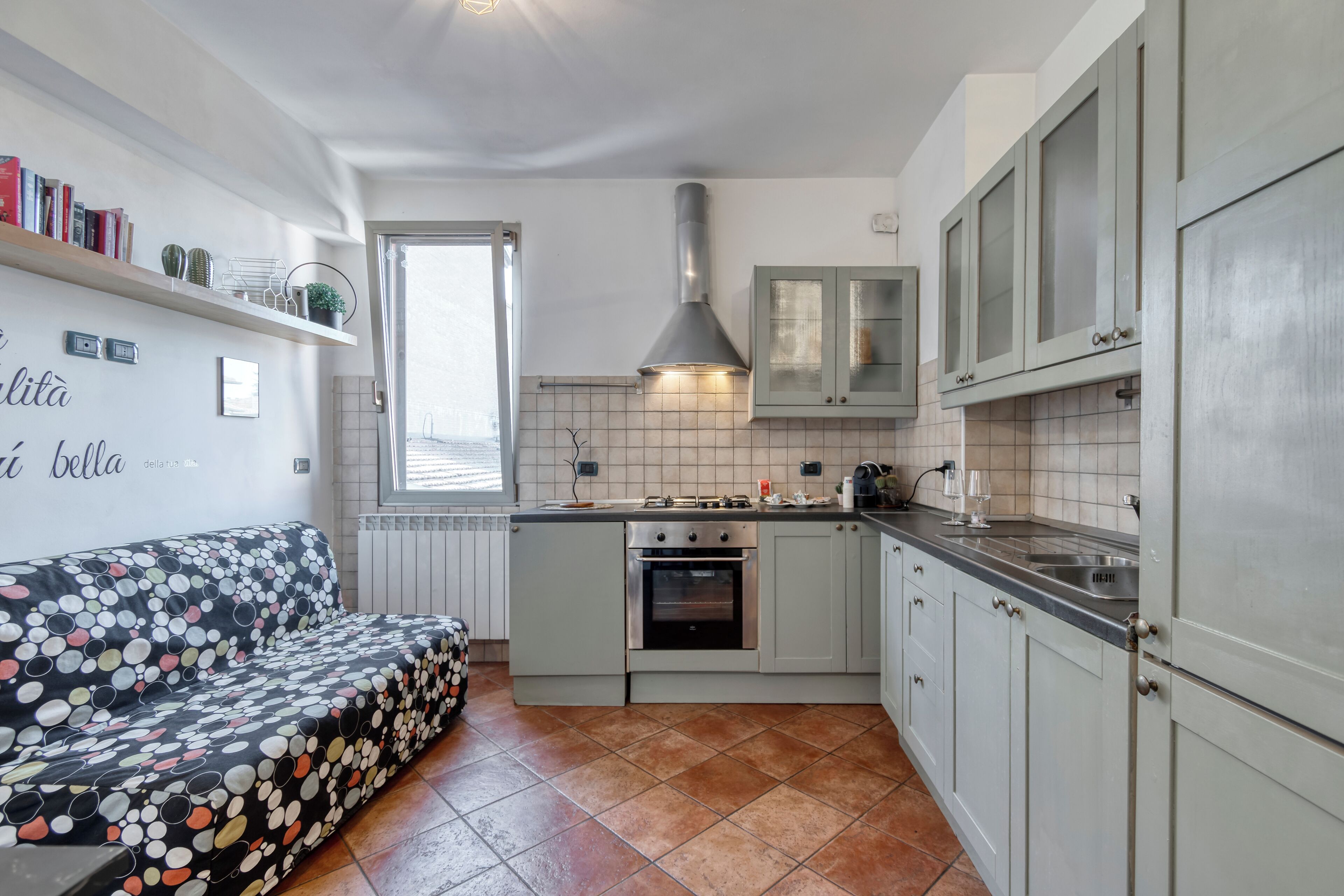 Una cucina compatta con forno integrato, una zona pranzo con divano e una finestra che offre luce naturale.