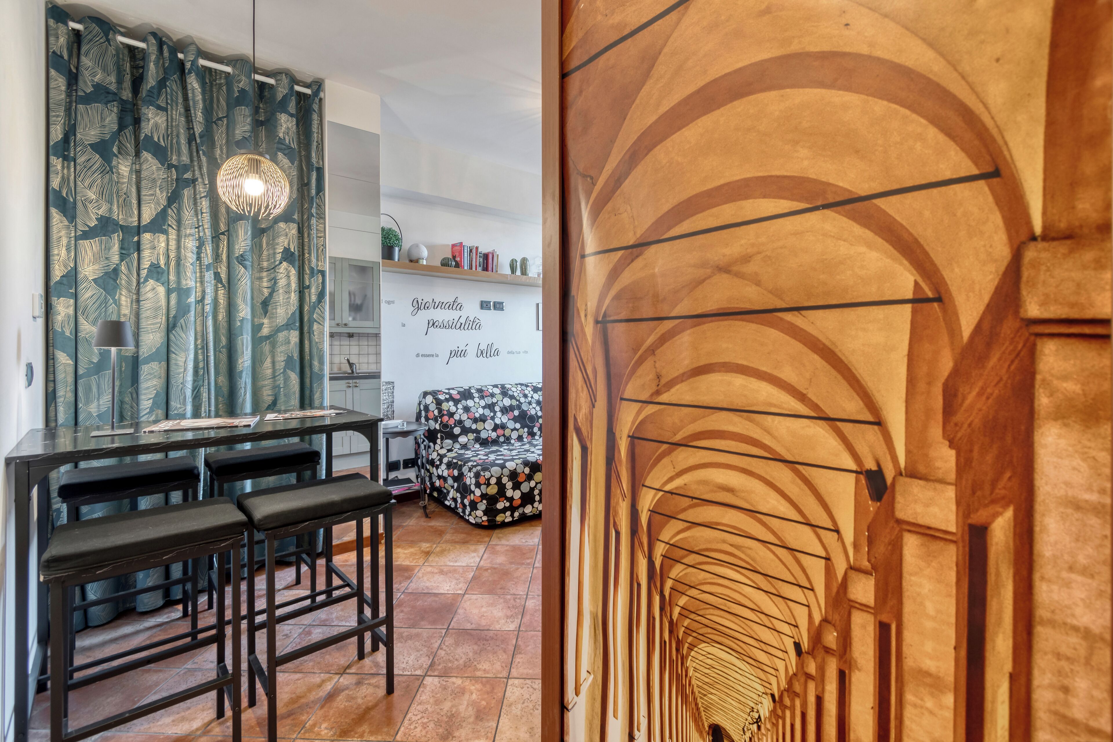 Una cucina moderna con zona pranzo, una tenda decorata e una frase motivazionale sulla parete.