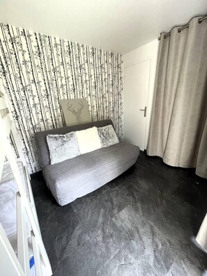 Ein Schlafzimmer mit einem Bett, einer Tür, einem Vorhang und einem Wandpapier mit Muster.