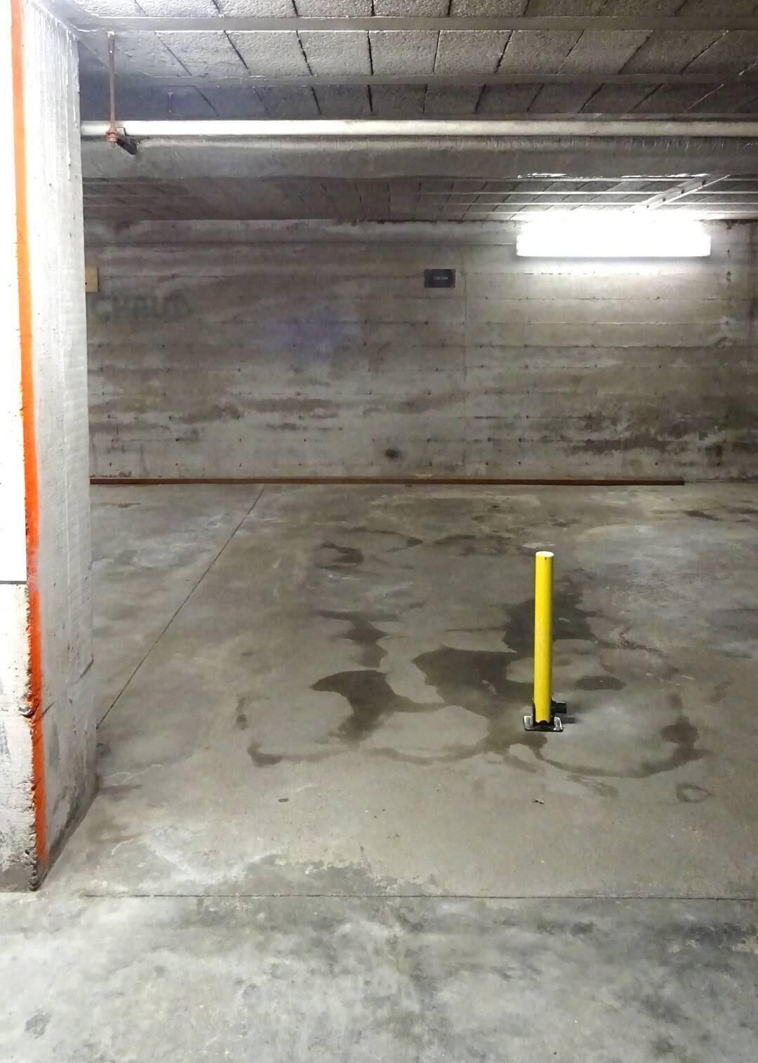 A concrete parking garage with a yellow pole in the center.