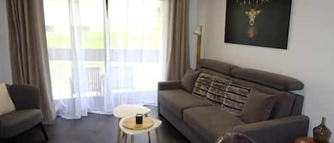Ein Wohnzimmer mit einer Couch, einem kleinen Tisch, einem Sessel und einem Gemälde an der Wand.
