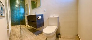 Een badkamer met toilet, wastafel en douche.