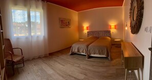 Une chambre à coucher avec un lit, des lampes de chevet, une chaise, une table de chevet et une vue sur l’extérieur.