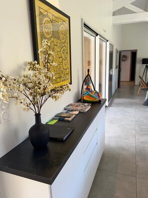 Ein Empfangsschalter mit Blumenvase, einem gerahmten Kunstwerk und einer bunten Tasche auf der Theke.