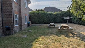 A backyard with a brick building, a hedge, and picnic tables. - House Sleeps 5 With Parking and Garden (Feltham)