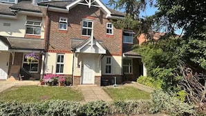 A two-story residential building with a symmetrical facade, a central entrance with a porch, and a small front garden. - House Sleeps 5 With Parking and Garden (Feltham)