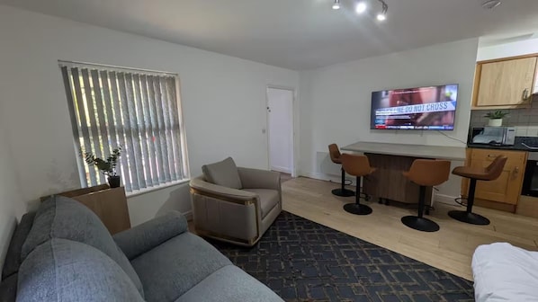 A modern living room with a grey sofa, a coffee table, and a TV mounted on the wall.