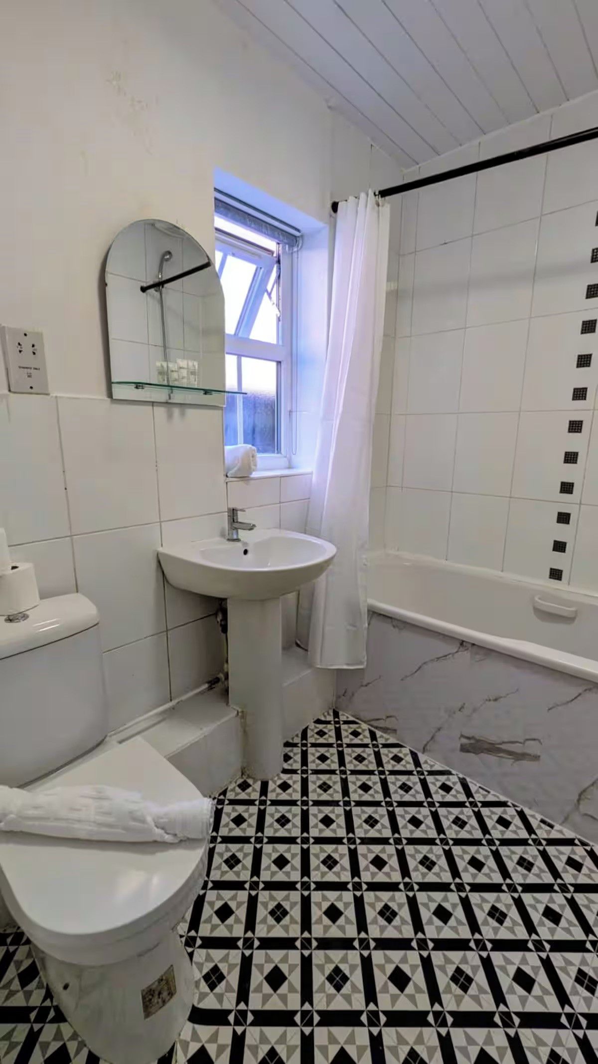 A bathroom with a toilet, sink, and shower area.