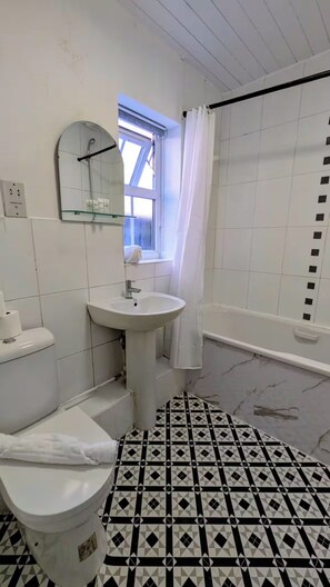 A bathroom with a toilet, sink, and shower area.
