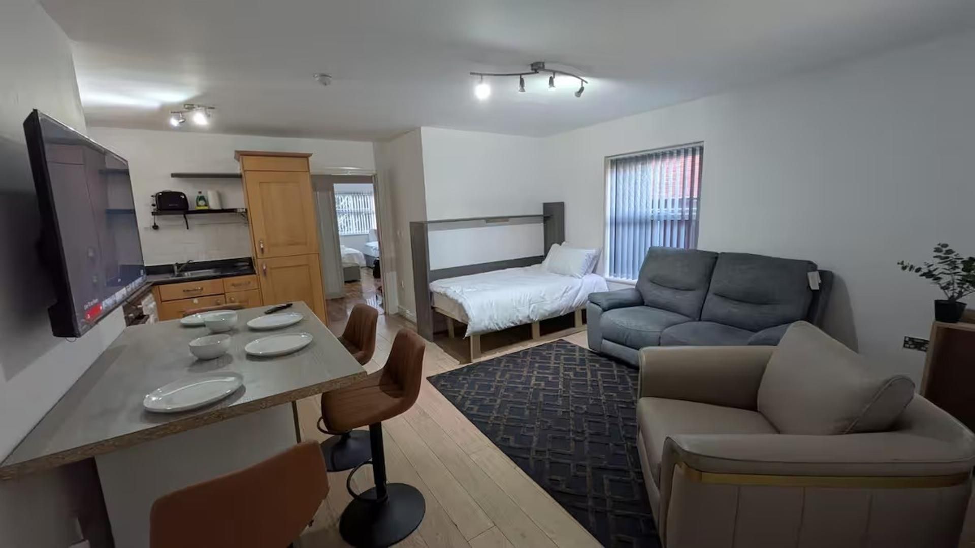 Um espaço compacto com cozinha compacta, cama, sofá e área de refeições.