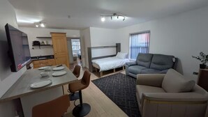 A compact living space with a kitchenette, a bed, a sofa, and a dining area. - House Sleeps 5 With Parking and Garden (Feltham)