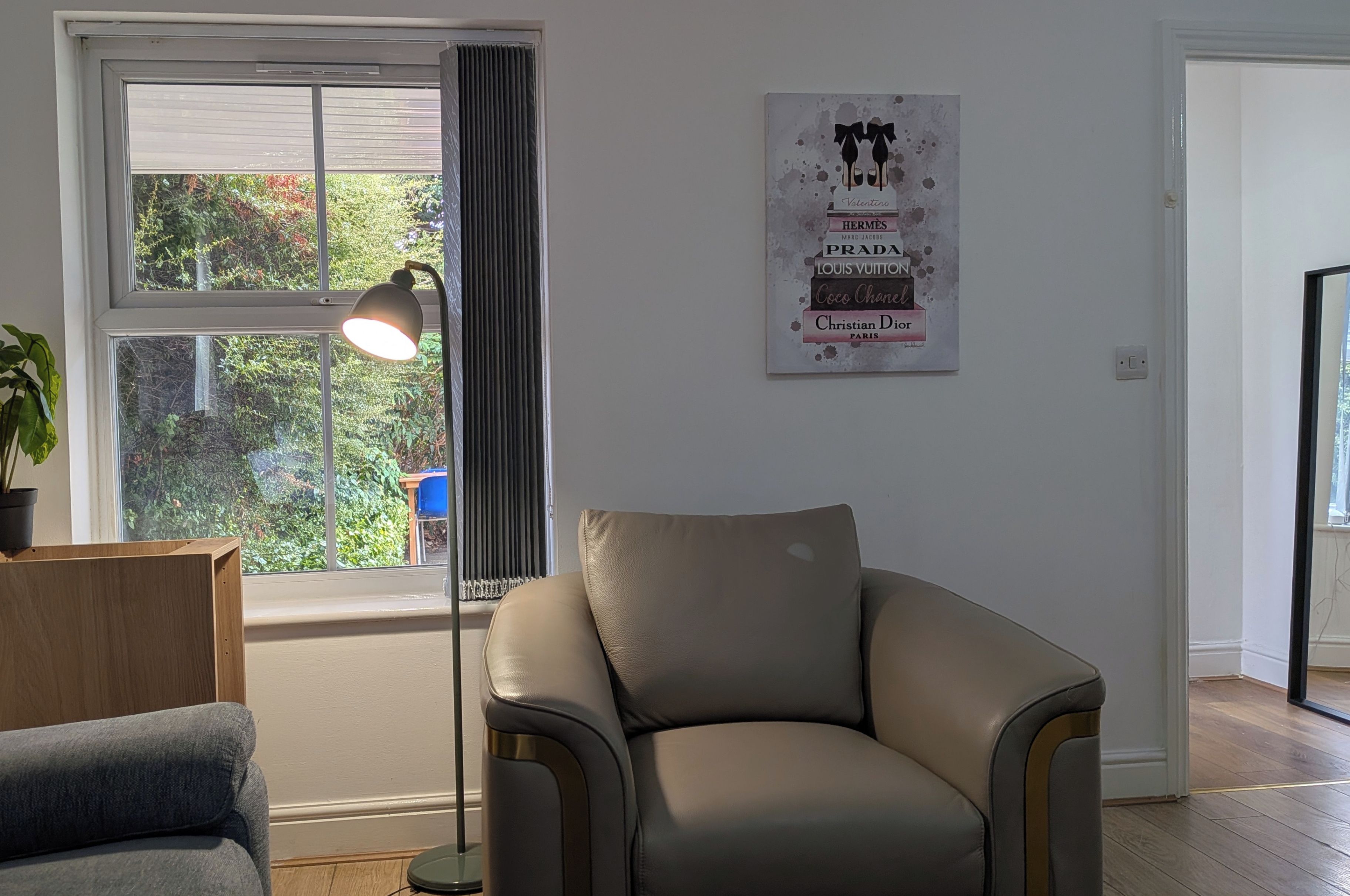 A room with a leather armchair, a floor lamp, and a poster on the wall.