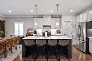 A modern kitchen with white cabinets, stainless steel appliances, and a central island with bar stools.