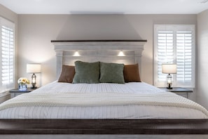 A bedroom with a large bed, two bedside lamps, and a clock on the nightstand. - Wings of Steel - 4BR Plus Bunk Room, Hot Tub, Fire Pit Table, 20 Minutes from Downtown Pittsburgh (Plum)