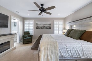 Un dormitorio con cama, una silla, chimenea y ventilador de techo.